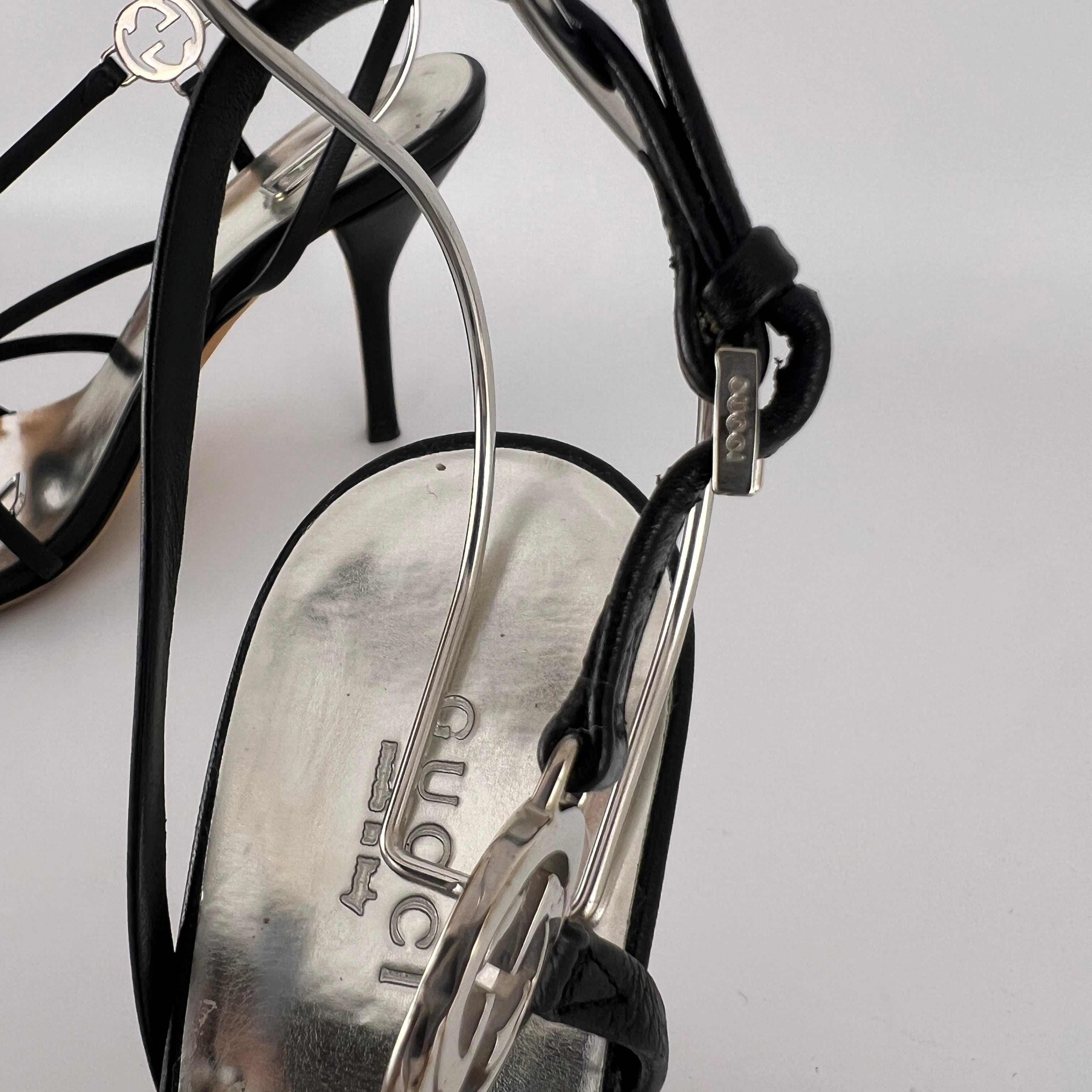 Gucci | GG Logo Silver Hardware Black Leather Metallic Insole Strappy Heels (37.5)